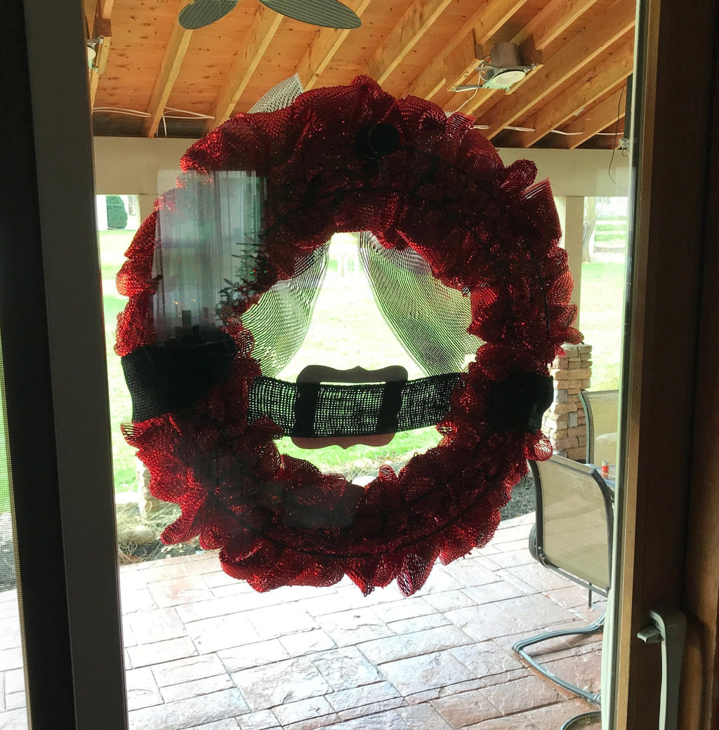 Red mesh wreath held on a glass patio door by a magnetic wreath hanger