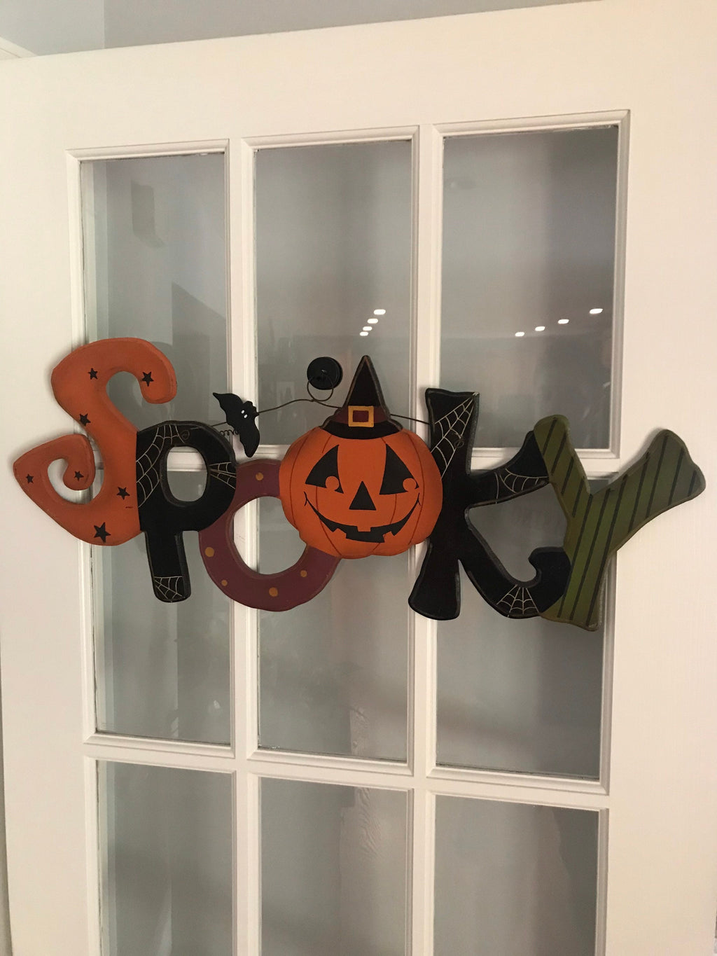 Wooden Spooky Halloween sign hanging on a glass French door from a magnetic hanger