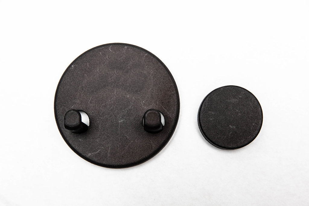 The two halves of the magnetic razor holder: the hook piece and the smaller backing magnet for the other side of the glass