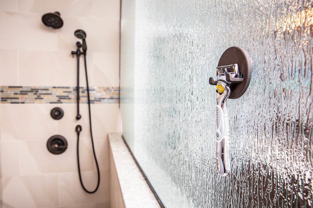Razor hanging on a magnetic razor holder on a textured glass shower door, no drilling or suction cups