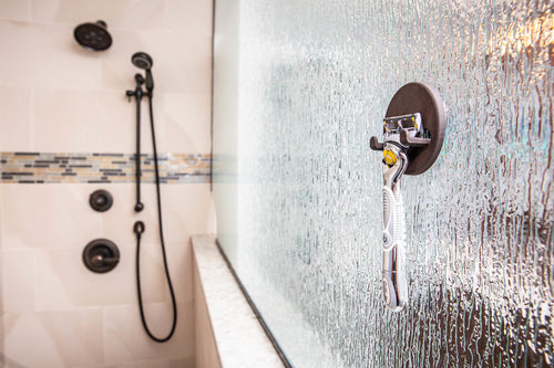 Razor hanging on a magnetic razor holder on a textured glass shower door, no drilling or suction cups