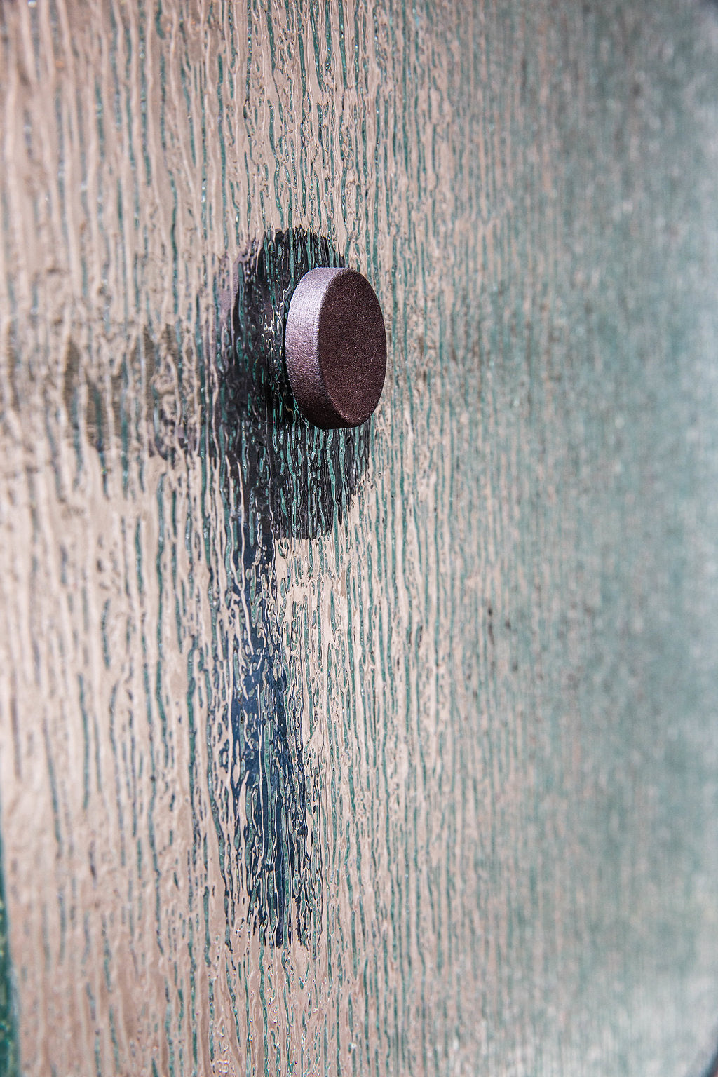 Side view of a razor hanging from a magnetic hook on frosted shower glass